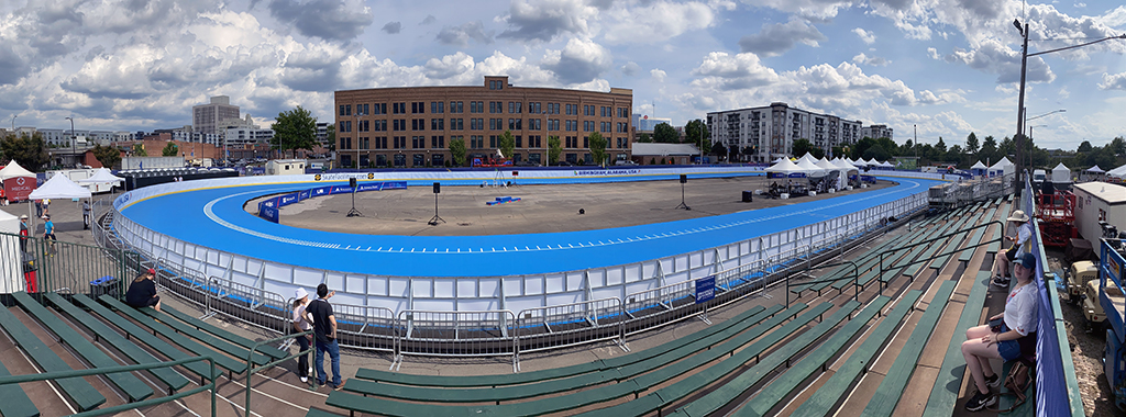 Banked speed track panorama at a competition, riders and crowd on the infield