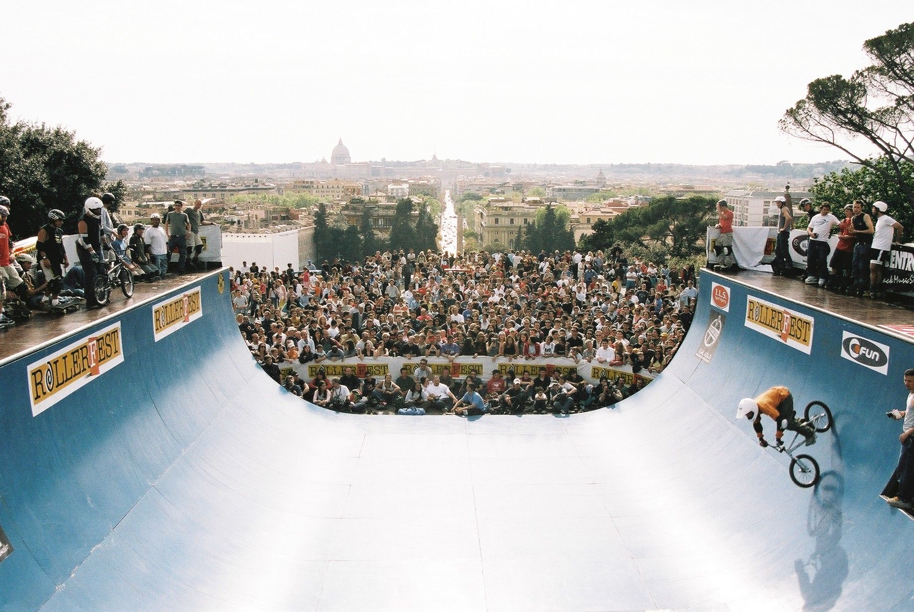 Vert ramp overlooking Rome, BMX rider dropping in above a crowd