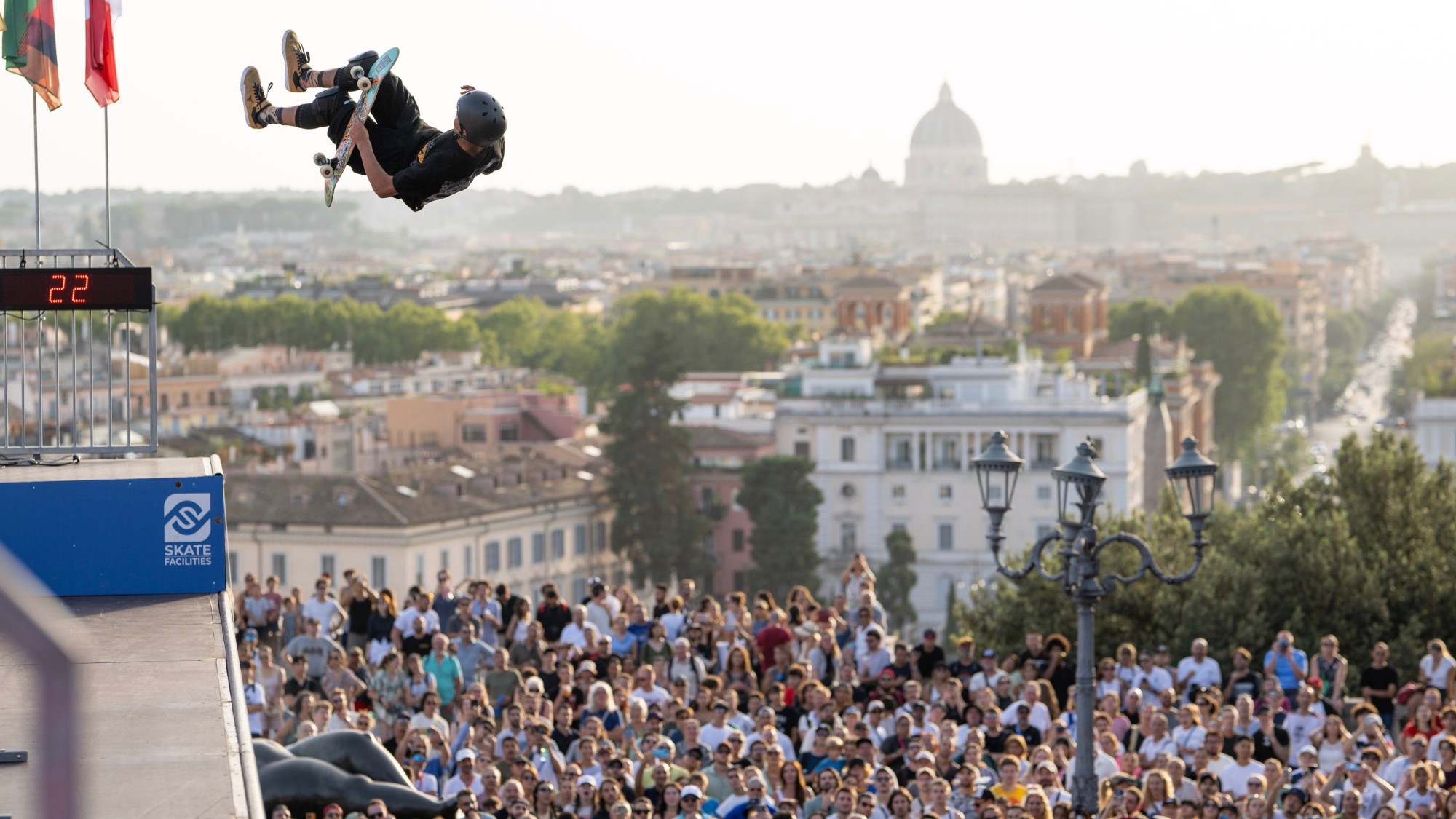 Skater catching air off a SkateFacilities vert ramp above the Rome skyline